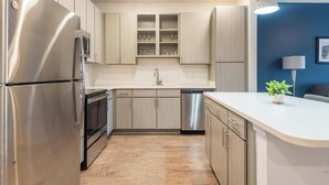 Een moderne keuken met roestvrijstalen apparatuur, licht houten kastjes en een wit aanrecht.