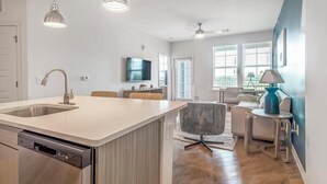 Une cuisine moderne dotée d’un grand îlot central, d’un lave-vaisselle encastré et de luminaires suspendus.
