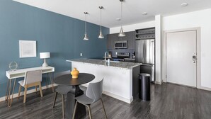 Una cocina moderna con una isla central, electrodomésticos de acero inoxidable y una zona de comedor con mesa y sillas.
