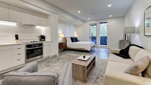 A modern, well-lit room with a kitchen, a bed, and a seating area. - Landing | Stylish Studio, Game Room, Gym (South Salt Lake)