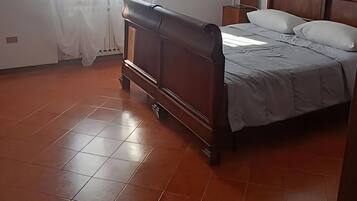 Un dormitorio con una cama de madera, una mesita de noche, una lámpara colgante y una ventana con cortinas.