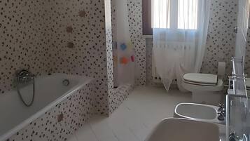 A bathroom with a bathtub, sink, toilet, and a shower area.