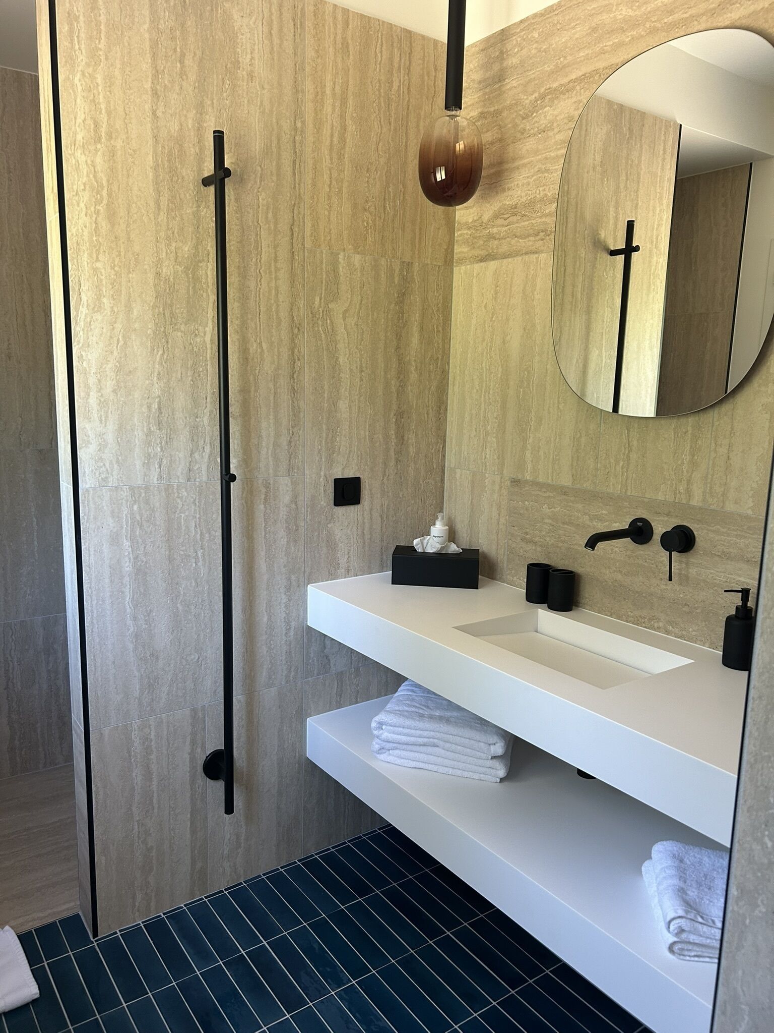 A modern bathroom with a wooden wall, a white sink, a mirror, and a towel rack.