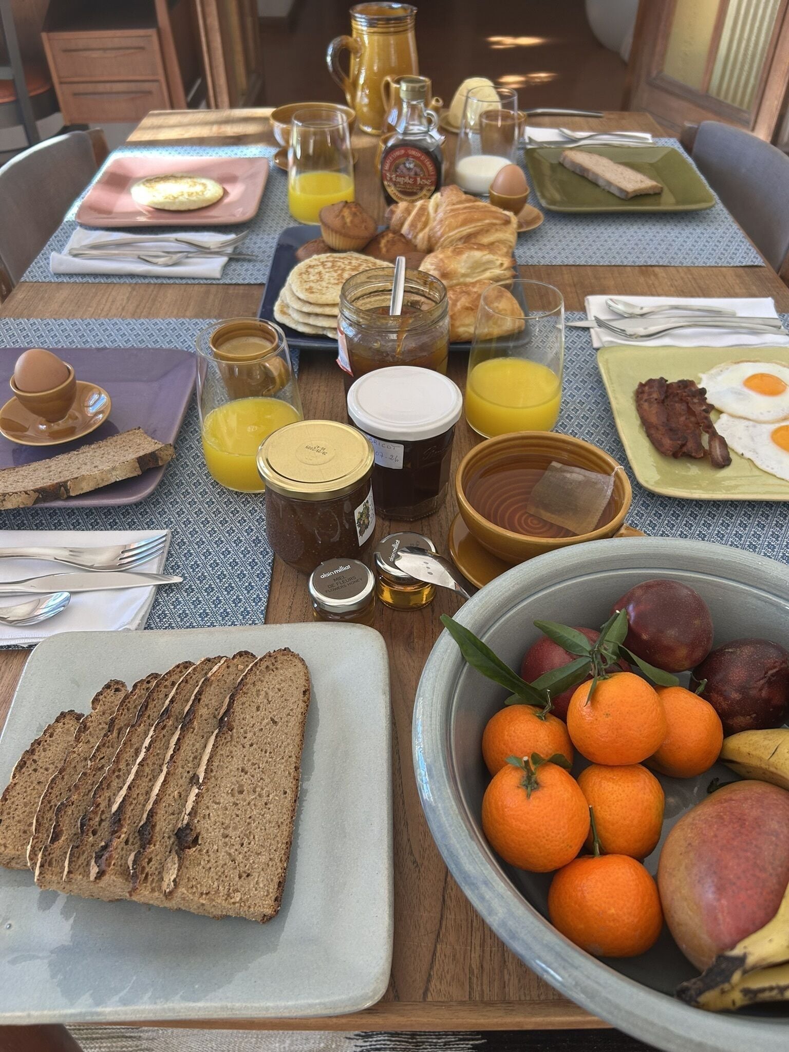 Una mesa de desayuno con diversos alimentos y bebidas, como tostadas, huevos y fruta.