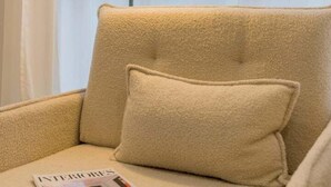 A beige armchair with a cushion, a magazine on the armrest, and a floor lamp in the background. - GuestReady - Modern and Cozy studio in Madrid (Madrid)