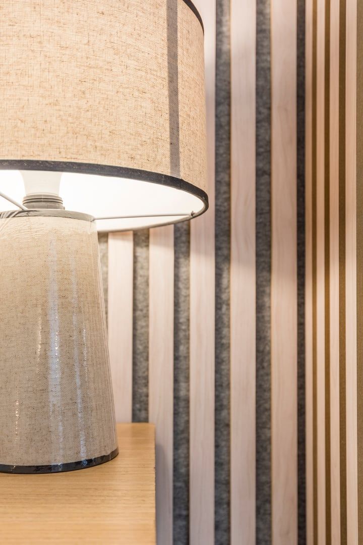 A lamp with a beige lampshade and a black base on a wooden surface.