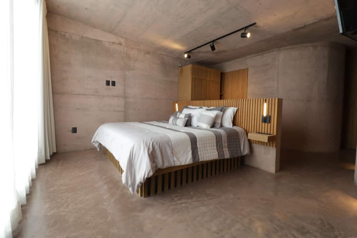 Ein modernes Schlafzimmer mit einem großen Bett, einem Holzkopfende und integrierter Beleuchtung.
