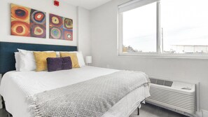 Une chambre d’hôtel avec un lit, des oreillers, une fenêtre et des œuvres d’art accrochées au mur.