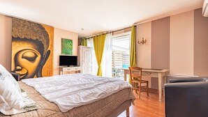 Ein Schlafzimmer mit einem Bett, einem Schreibtisch, einem Stuhl, einem Fernseher und einem Buddha-Gemälde.