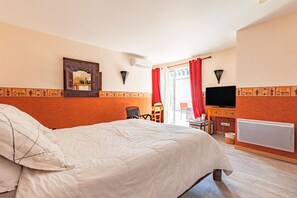 A hotel room with a bed, a desk, a chair, a television, and a window with curtains.
