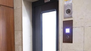 Un ascensor con pantalla digital, puerta y panel de control en la pared.