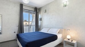 Un dormitorio moderno con cama, lámpara de noche y ventana con cortinas.