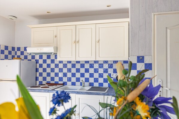 Una cocina con armarios blancos, un salpicadero azul y blanco a cuadros, y una estufa blanca.