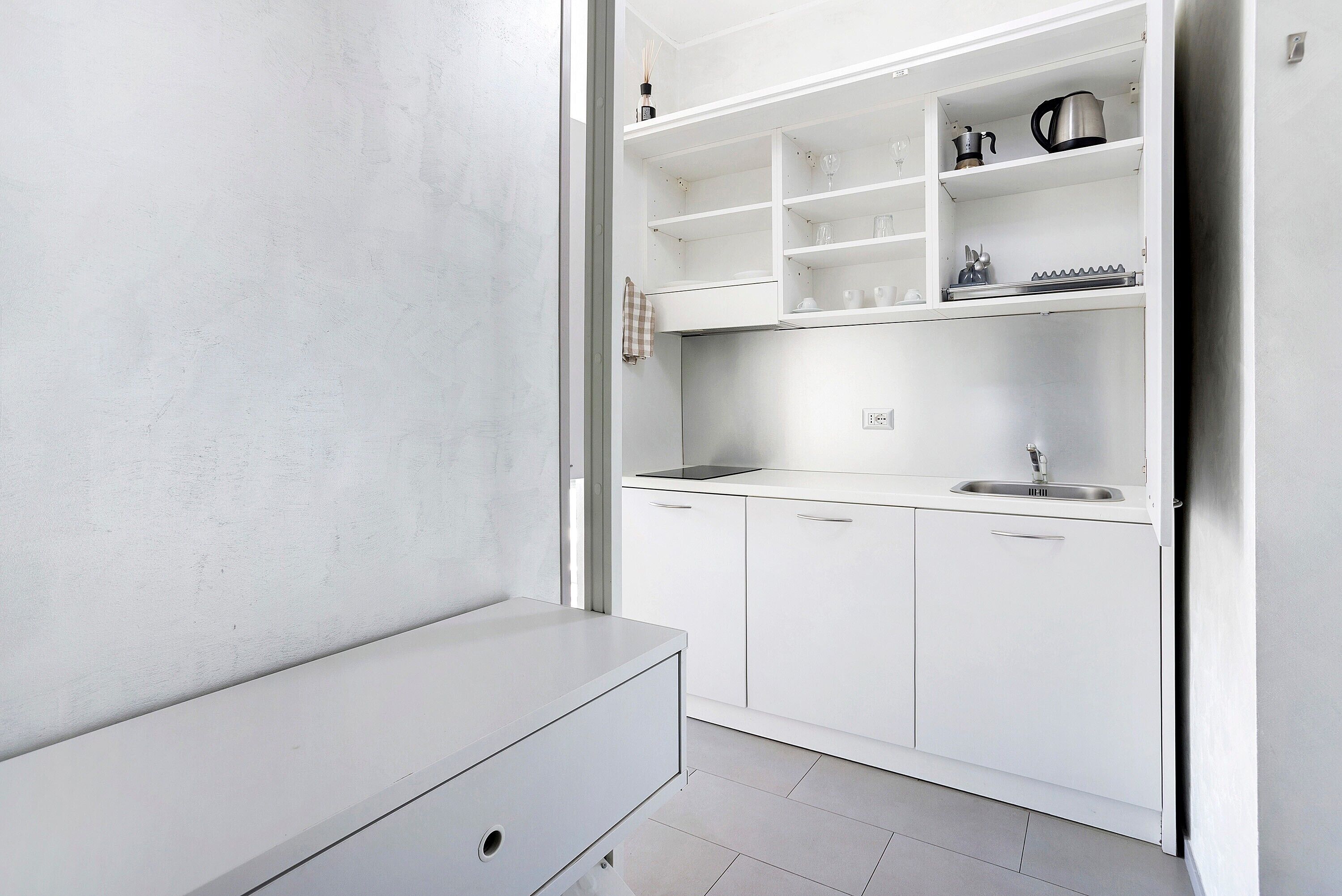 A modern kitchen with white cabinetry, a stainless steel sink, and a countertop.