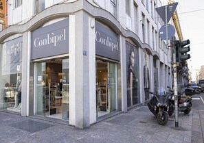 A storefront with the name 'Conbipel' on the facade, a motorcycle parked outside, and a traffic light in the background. - Apartment 'Smart Central 5' with Balcony, Wi-Fi and Air Conditioning (Milan)