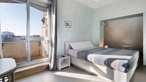 A modern bedroom with a bed, a small bedside table, a chair, a view through a large window, and a picture on the wall. - Apartment 'Smart Central 5' with Balcony, Wi-Fi and Air Conditioning (Milan)