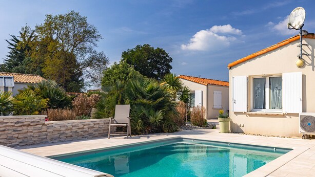 En swimmingpool med en stenmur, en stol och en byggnad med en satellantenn.