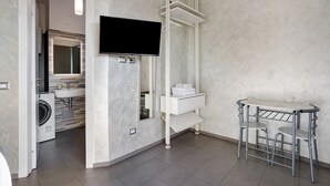 Une salle de bain moderne équipée d’un lave-linge, d’un évier, d’un miroir et d’un téléviseur fixé au mur.