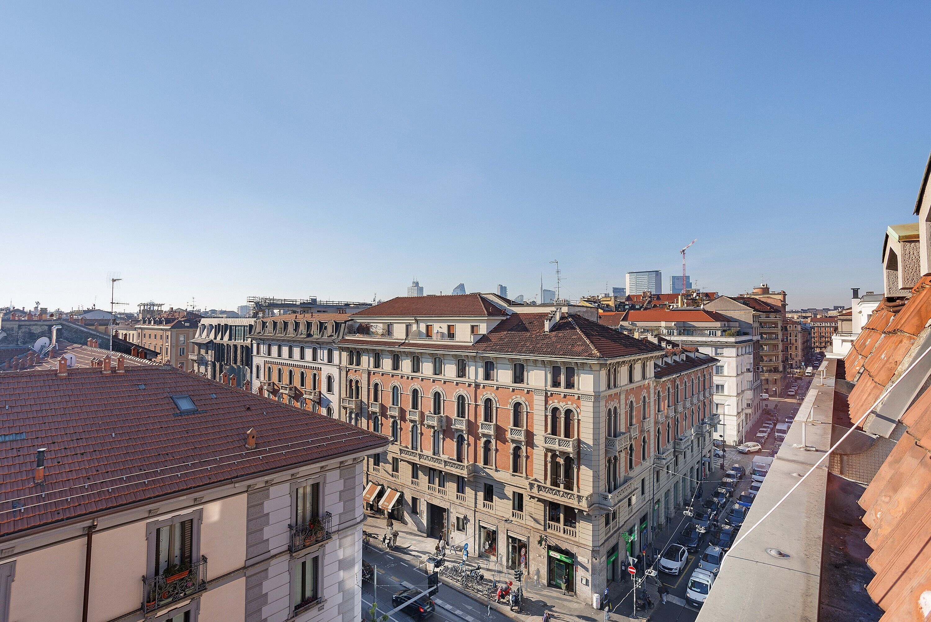 Eine Stadtansicht mit historischen Gebäuden, wolkenlosem Himmel und einer belebten Straße.