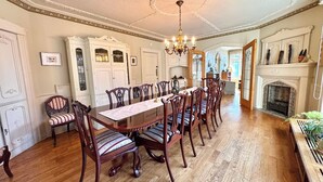 A formal dining room with a long wooden table, ornate chairs, and a chandelier.