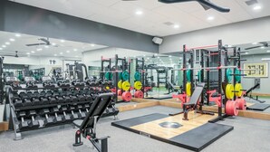 A gym with weightlifting equipment, mirrors, and a variety of machines.