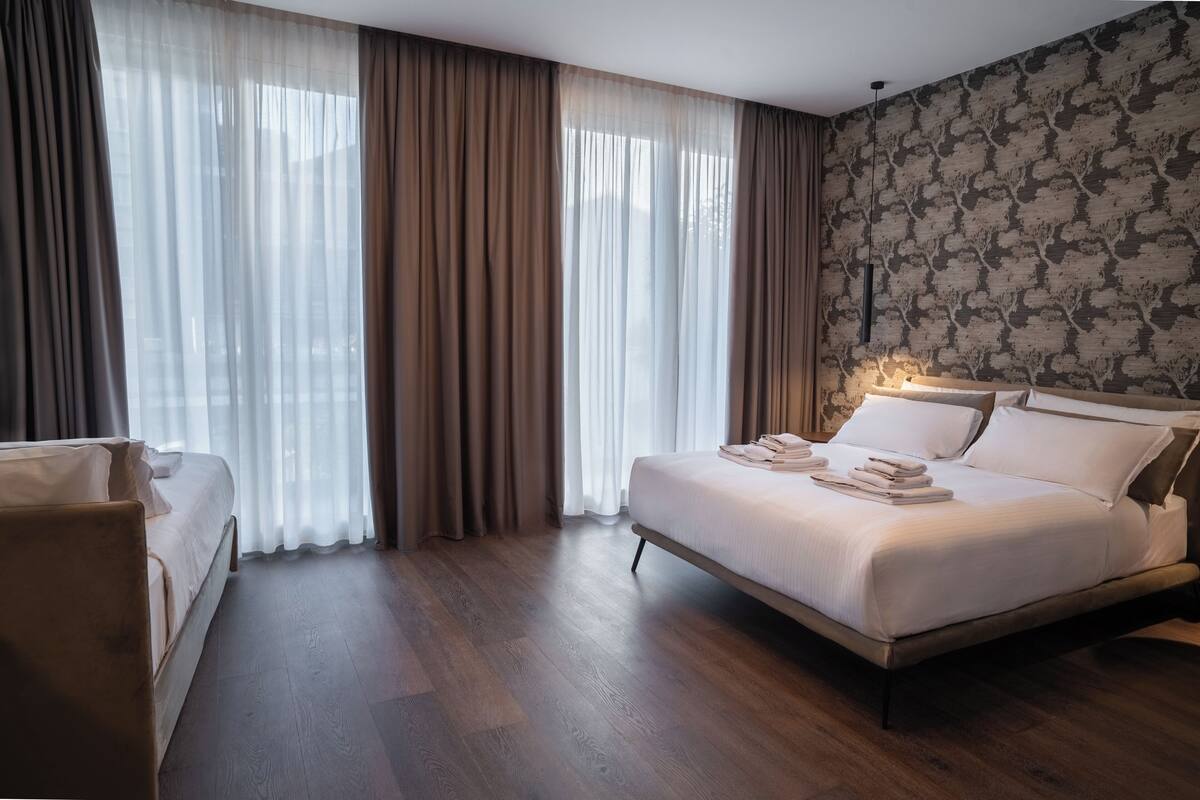 Ein modernes Hotelzimmer mit einem großen Bett, einem Nachttisch und einem Sessel.