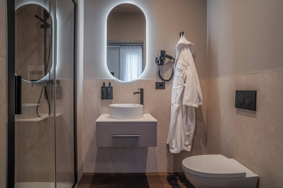 Ein modernes Badezimmer mit einer gläsernen Duschkabine, einem weißen Waschbecken und einer Toilette.