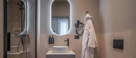 Et moderne badeværelse med et glasafskærmet brusebad, en hvid vask og et toilet.