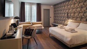 Une chambre d’hôtel comprenant un lit, un bureau avec un ordinateur portable, une chaise, une table de chevet avec une lampe et une armoire.