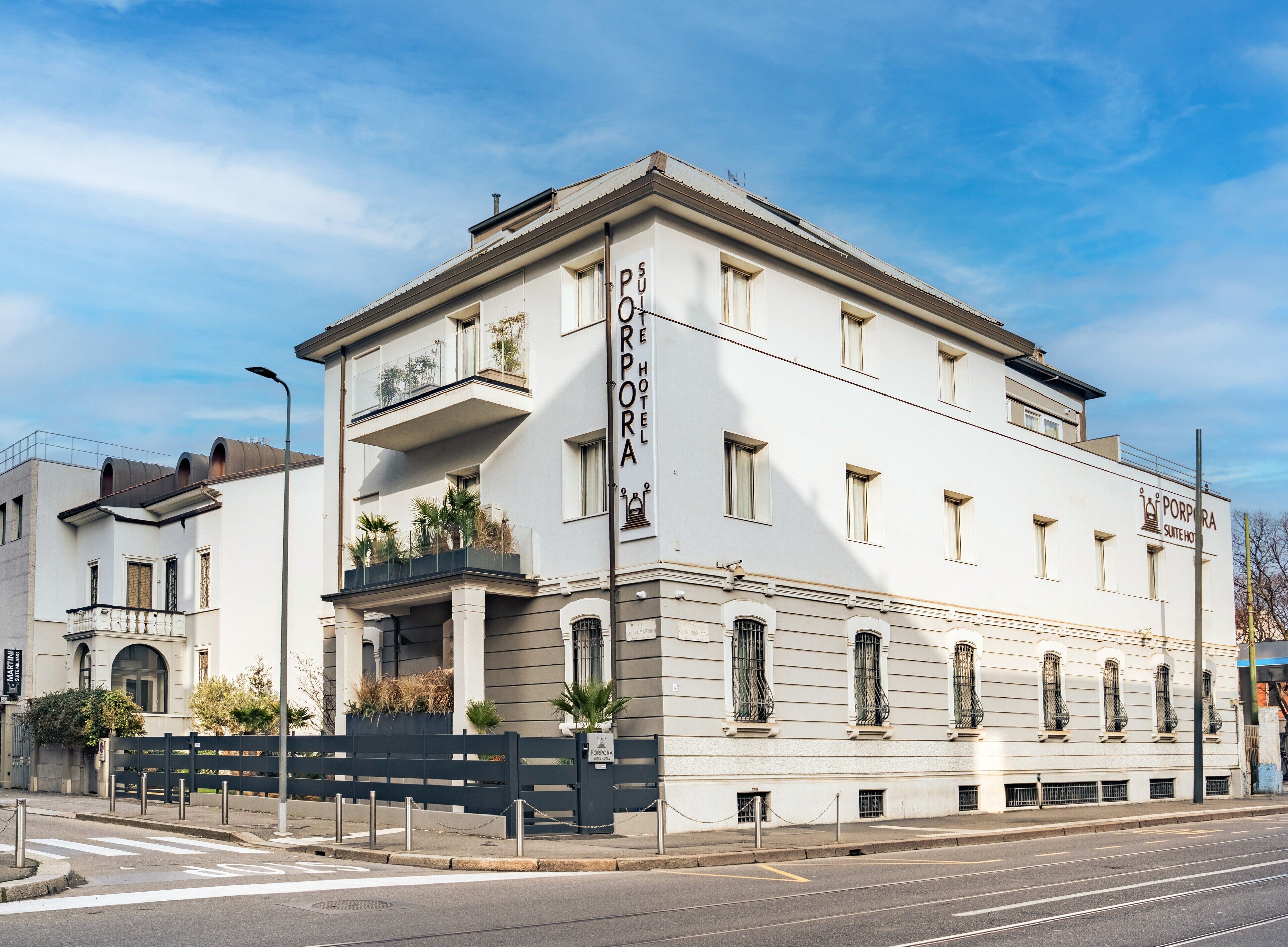 A white building with balconies and a sign reading "PORPORA SUITE HOTEL".