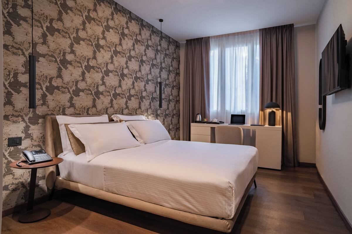Ein modernes Hotelzimmer mit einem großen Bett, einem Schreibtisch und einem Fernseher.