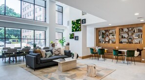 En rummelig lobby med en moderne sofa, et sofabord, og et siddeområde med stole. Der er et stort vindue med udsigt til gaden.
