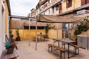 An outdoor patio area with a table and benches, surrounded by potted plants and a pergola. - Casa Giusi Terrace Charm by Wonderful Italy (Catania)