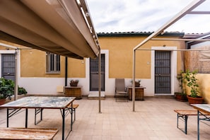 A patio area with outdoor seating, potted plants, and a building with a tiled roof. - Casa Giusi Terrace Charm by Wonderful Italy (Catania)