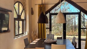 Een eetgedeelte met een grote tafel, stoelen en hangende lampen.