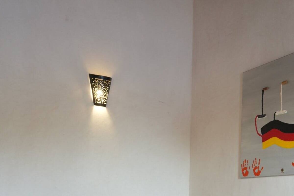Une chambre à coucher avec un lit, une lampe fixée au mur et un tableau.