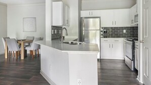 Una cocina moderna con armarios blancos, un refrigerador de acero inoxidable y una isla integrada con pileta.