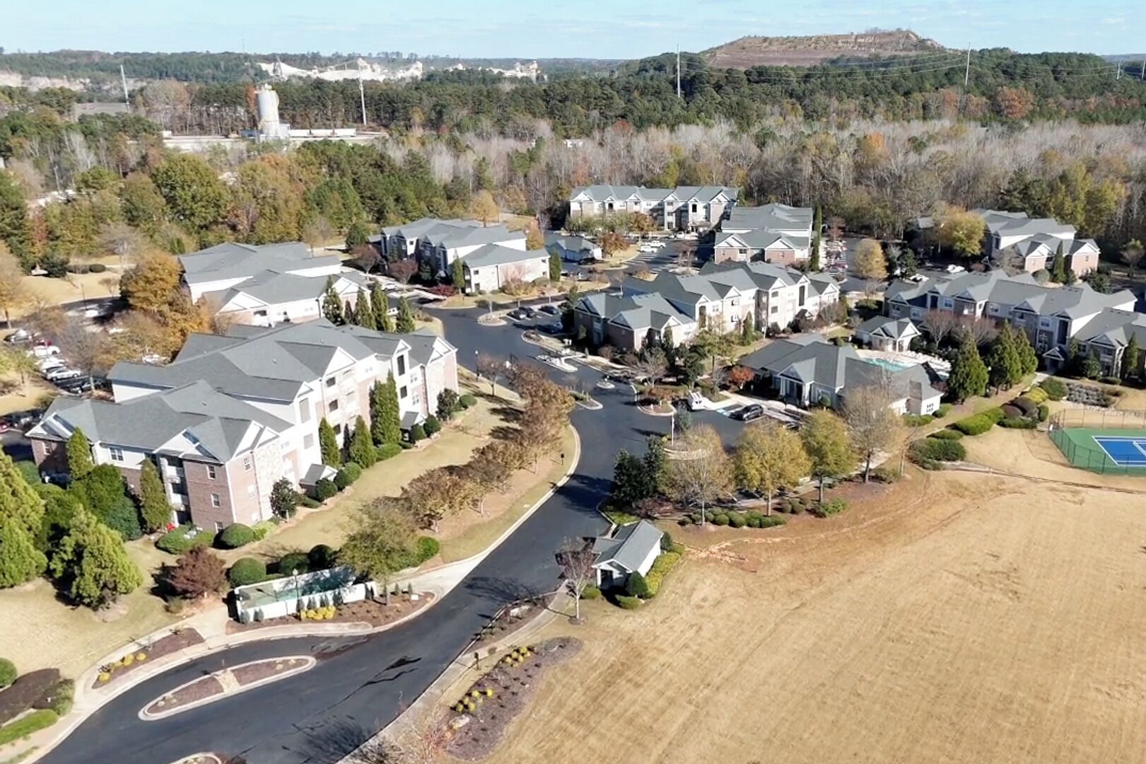 A residential area with multiple two-story houses, a curved road, and a large open field.