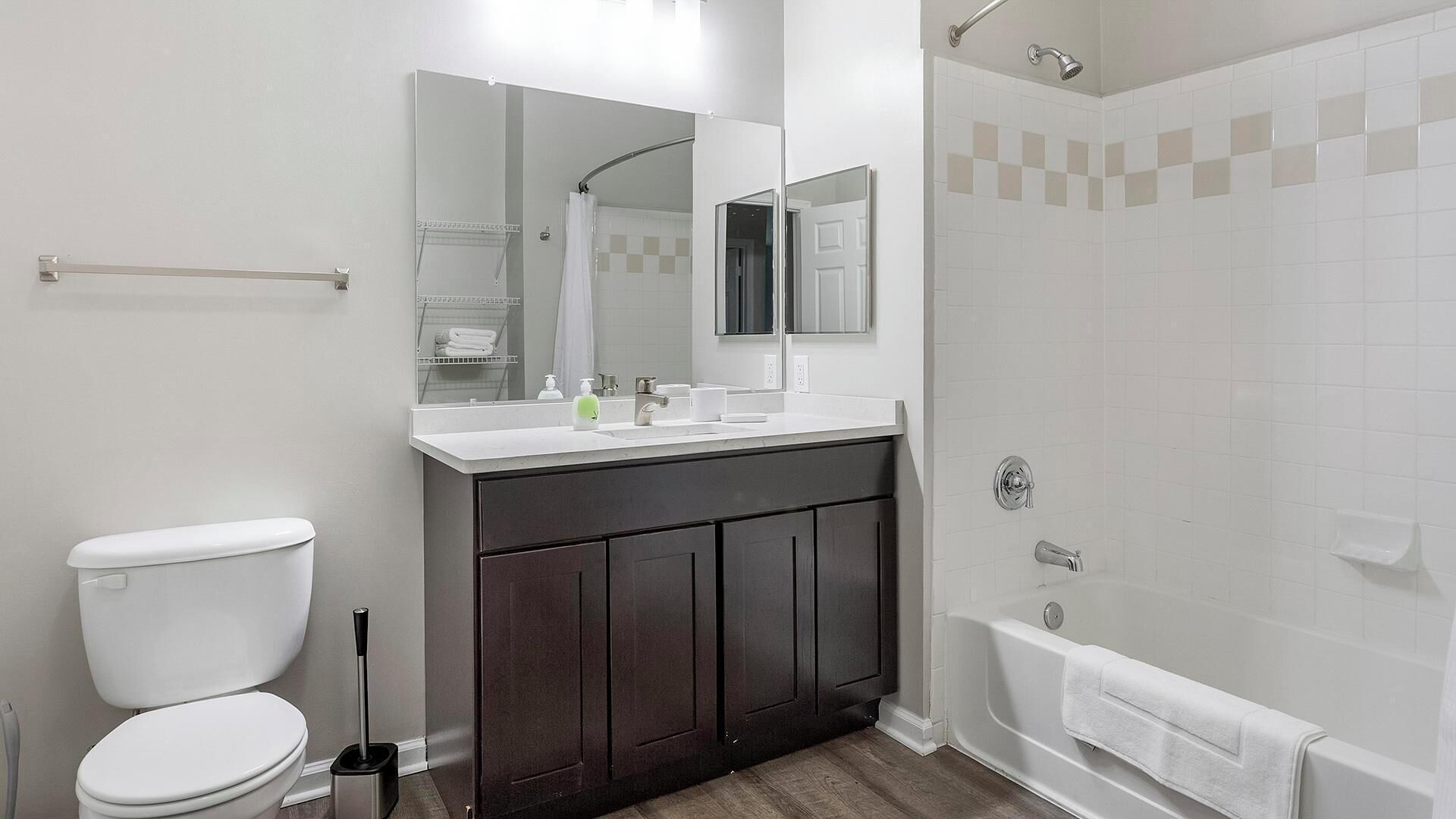 Un baño moderno con inodoro, lavamanos, espejo y ducha.