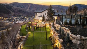 Ein Wohngebiet mit einem Haus, einem Spielplatz und Blick auf eine Stadt und Berge im Hintergrund.