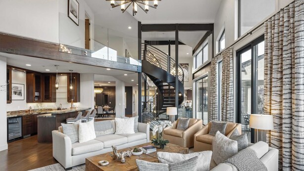 Amplia sala de estar con cocina moderna, una escalera y un gran ventanal con cortinas.