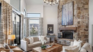 Un salón amplio con chimenea de piedra, ventanas grandes y una zona de estar acogedora.
