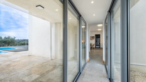 Een modern gebouw met een glazen doorgang naar een zwembad.