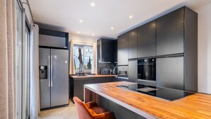Een moderne keuken met een centraal eiland, donkere kasten en uitzicht op de omgeving.