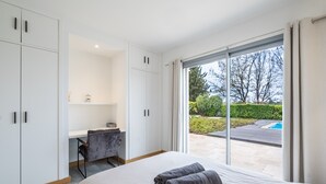 Een slaapkamer met een groot bed, een bureau en uitzicht op een zwembad.