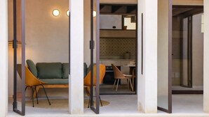 Un interno moderno con un divano verde, un tavolo da pranzo con sedie e un angolo cottura.
