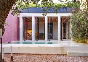 Un área de piscina moderna al aire libre, con zona de estar y sección cubierta con puertas de cristal.