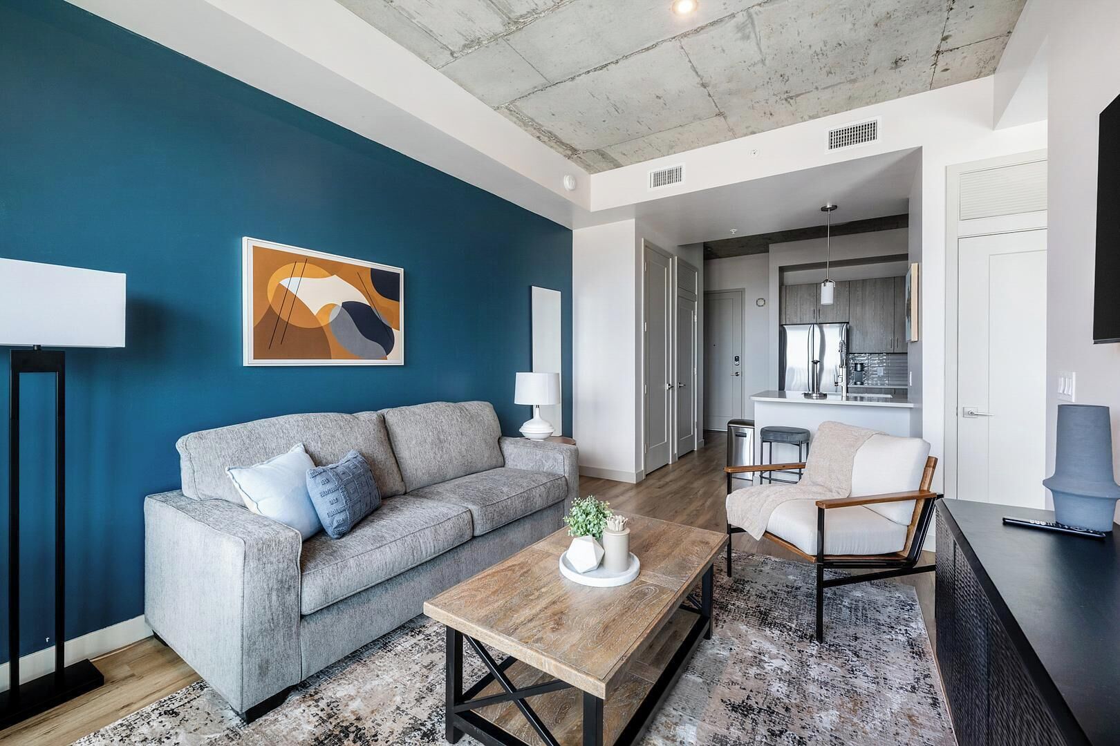Ein modernes Wohnzimmer mit einem grauen Sofa, einem Holztisch und einer blauen Akzentwand.