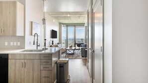 A modern kitchen with a large island, a dining area with a view, and a minimalist living space. - Landing | Stylish 1BD, Clubhouse, Game Room (Salt Lake City)