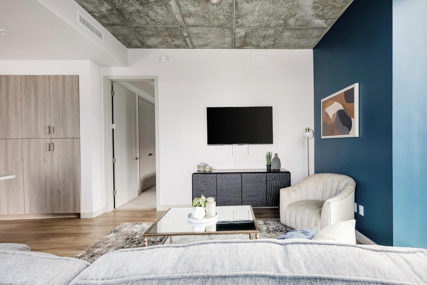 Een moderne woonkamer met een bank, salontafel, televisie en kast.